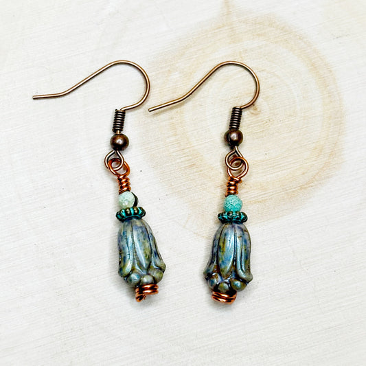 Pair of earrings with blue and green beads on a white background