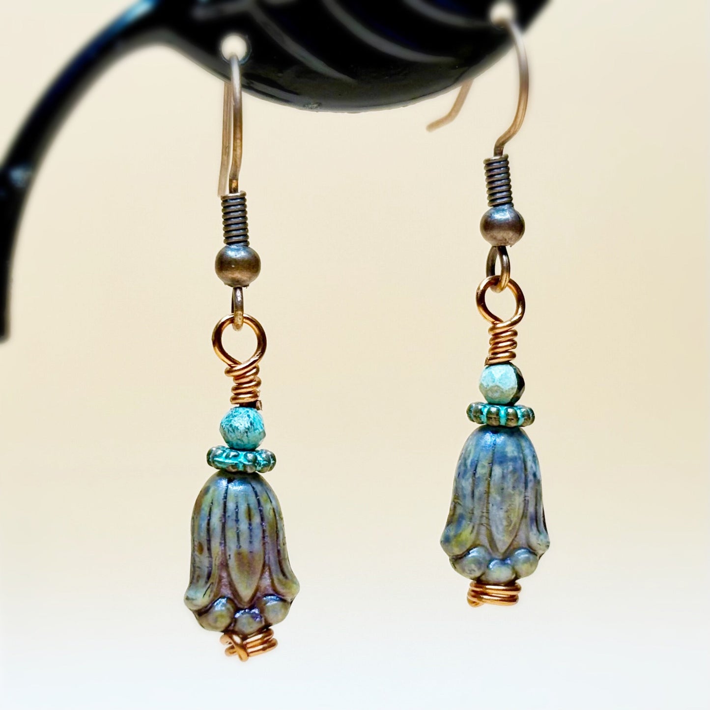Pair of earrings with blue and copper beads on a neutral background