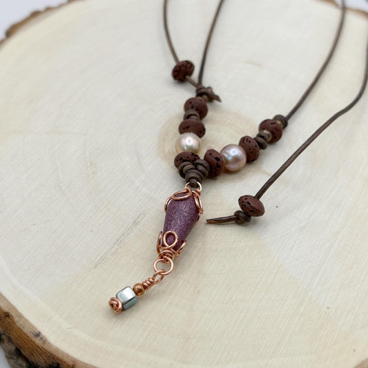 Necklace with brown beads and a copper accent on a wooden surface