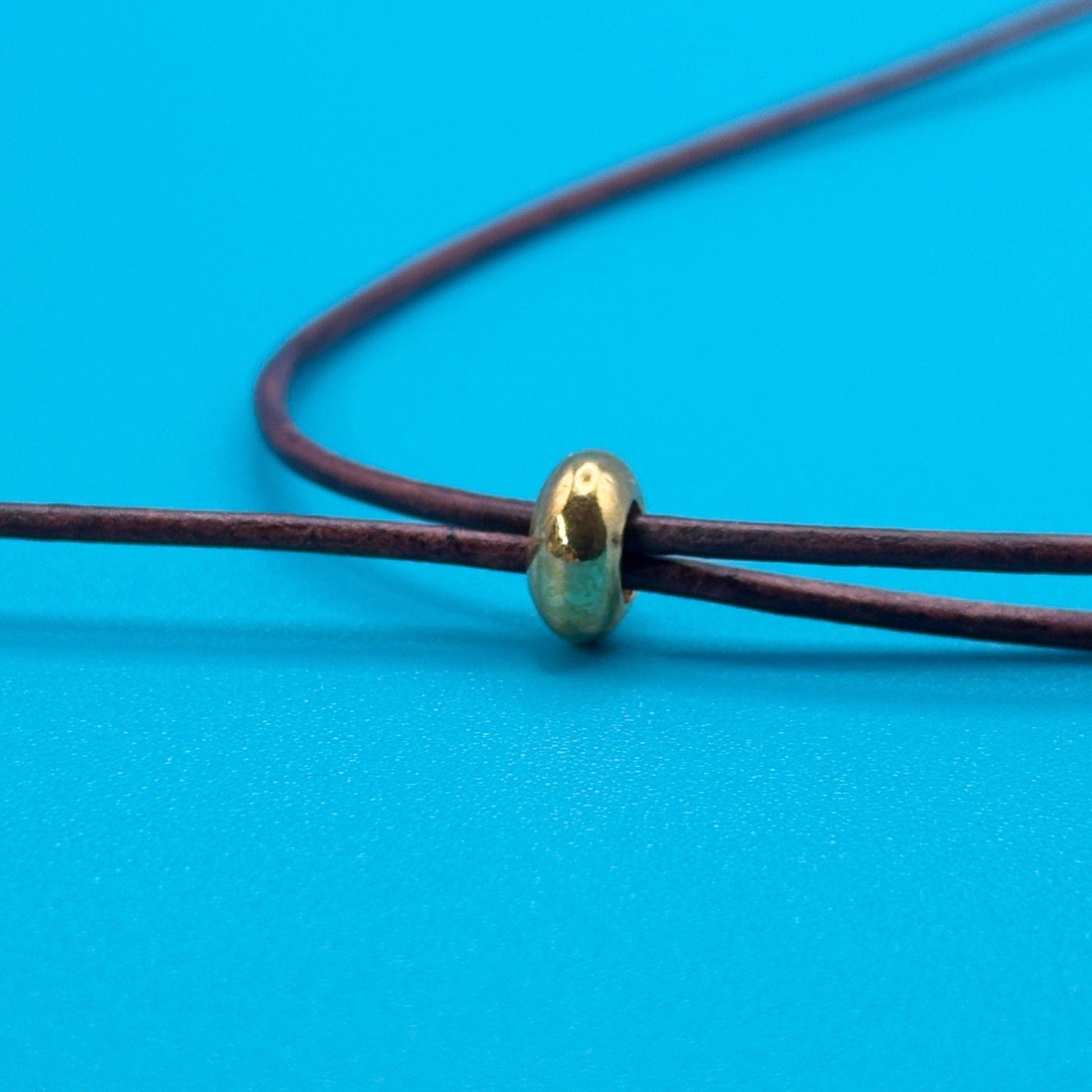 Gold bead on brown cord against a blue background