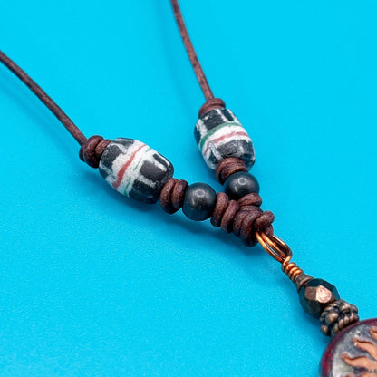 Beaded necklace with dark beads and a decorative clasp on a blue background