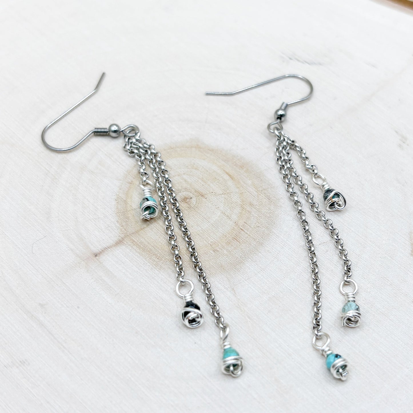 Silver earrings with chain and bead details on a light background