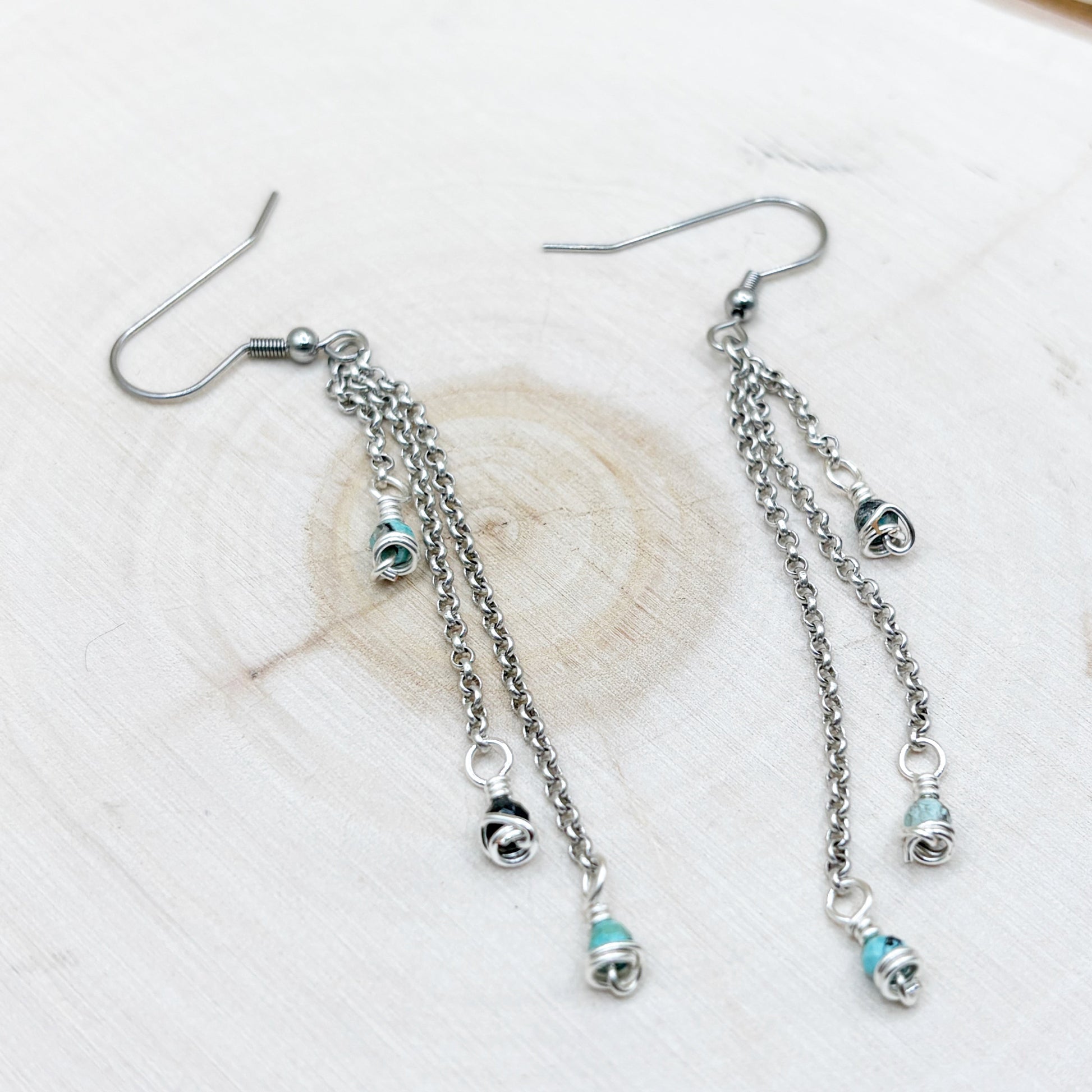 Silver earrings with chain and bead details on a light background