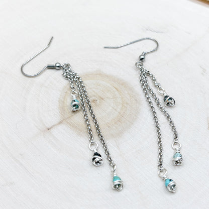 Silver earrings with chain and bead details on a light background