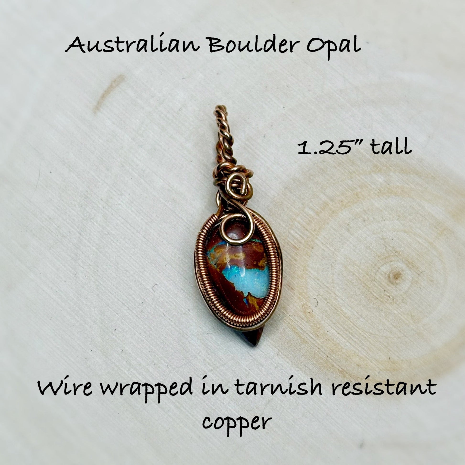 Australian Boulder Opal pendant with wire wrapping on a wooden surface