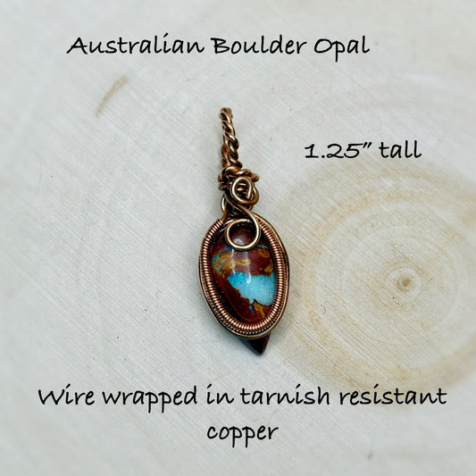 Australian Boulder Opal pendant with wire wrapping on a wooden surface