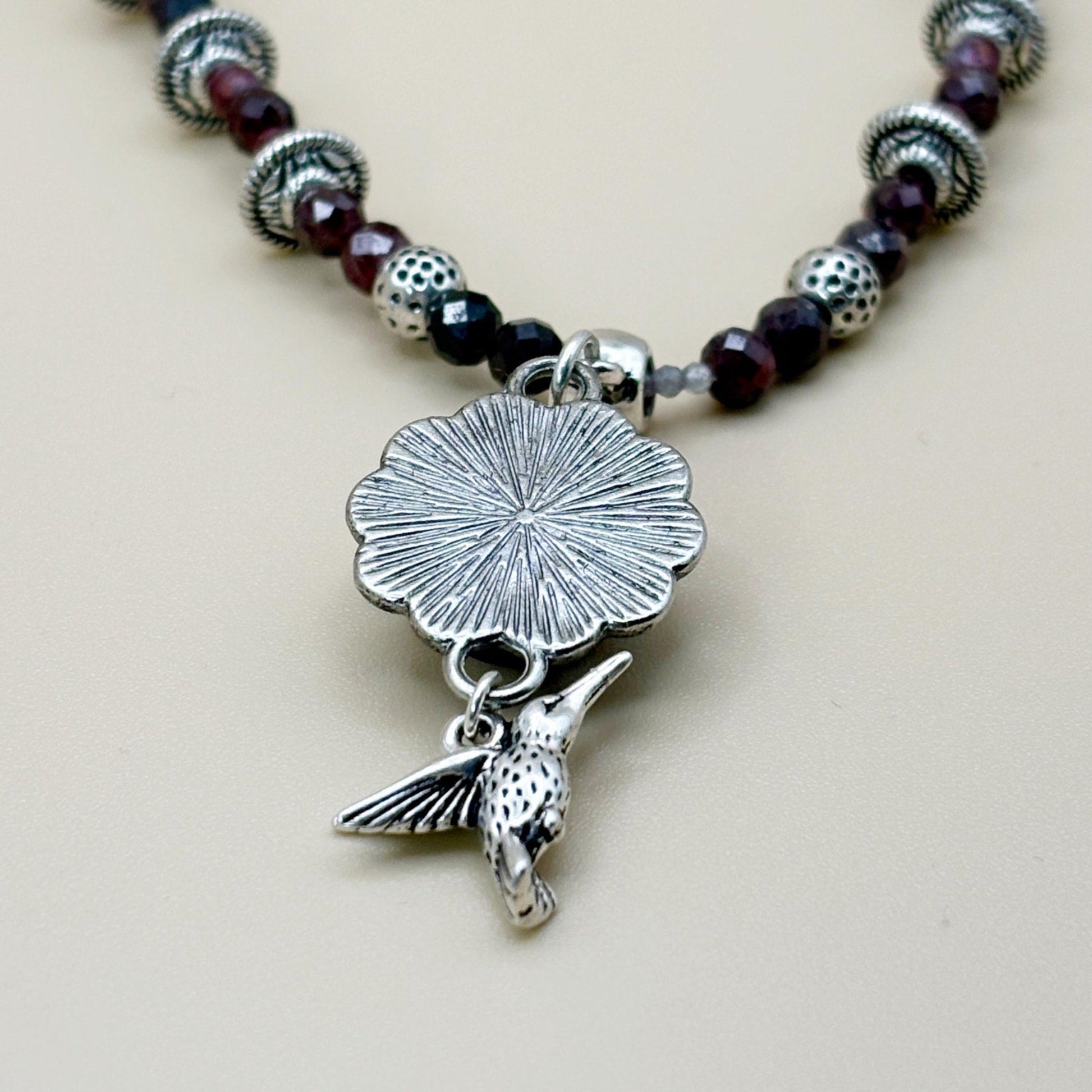 Necklace with silver pendant and beads on a beige background