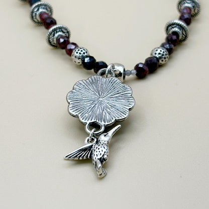 Necklace with silver pendant and beads on a beige background