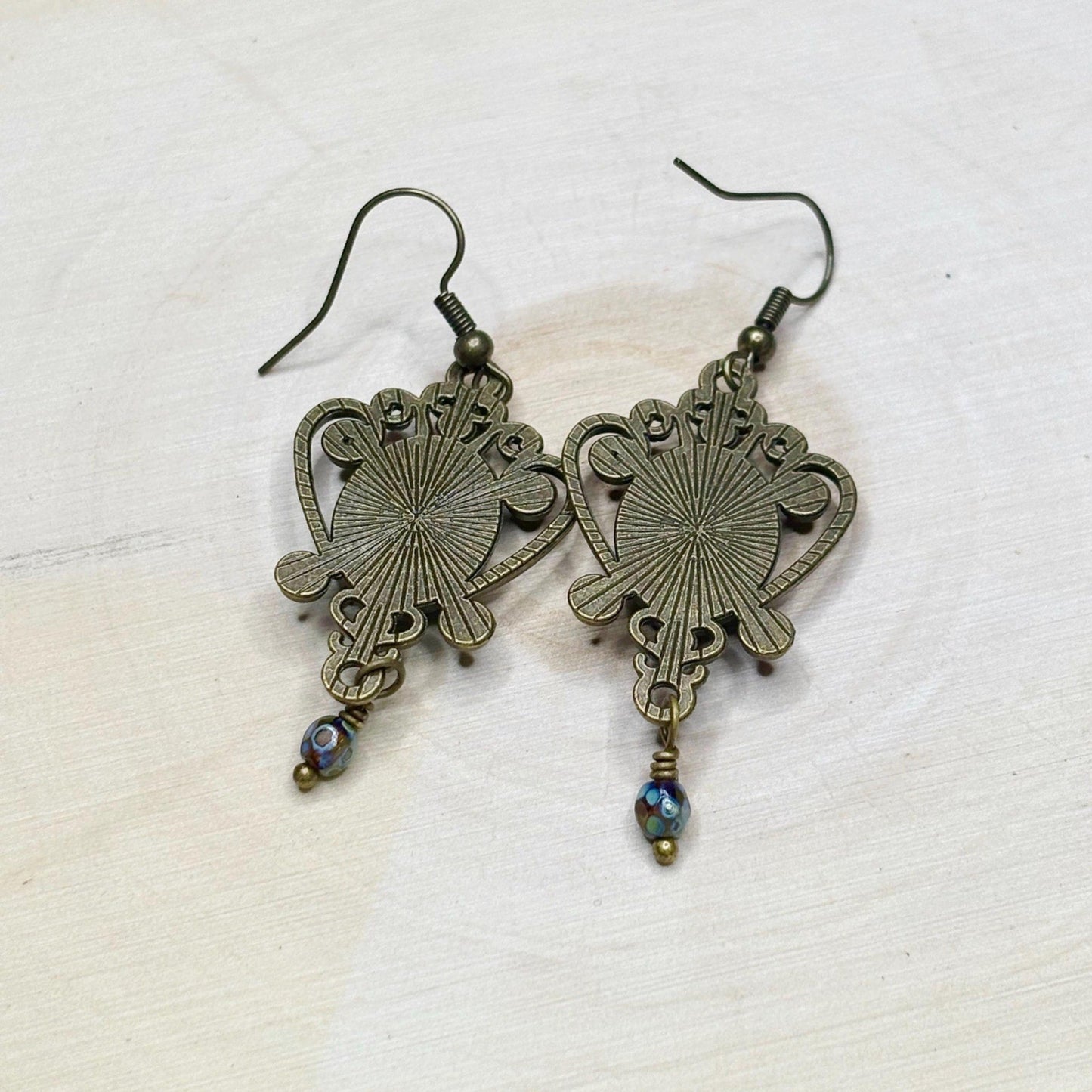 Pair of ornate bronze earrings on a light background
