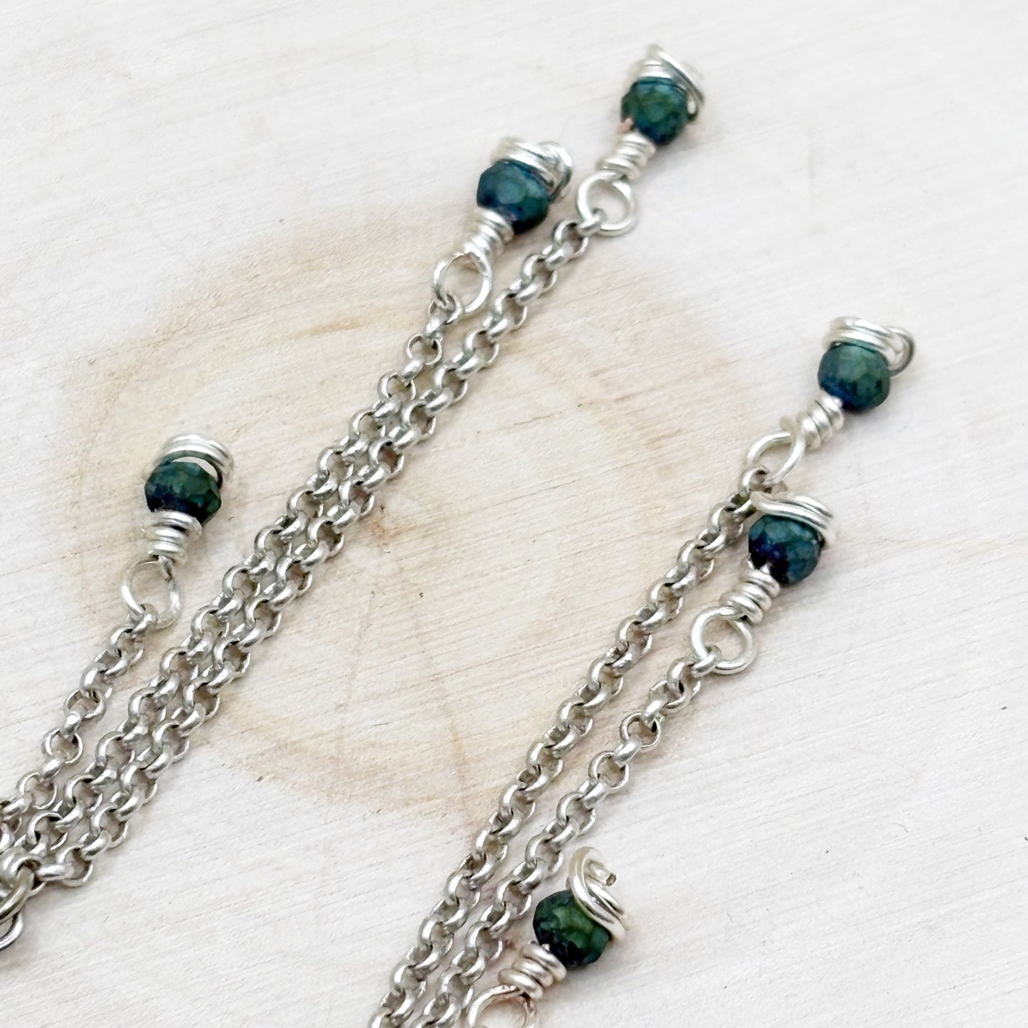 Silver chains with green beads on a light background