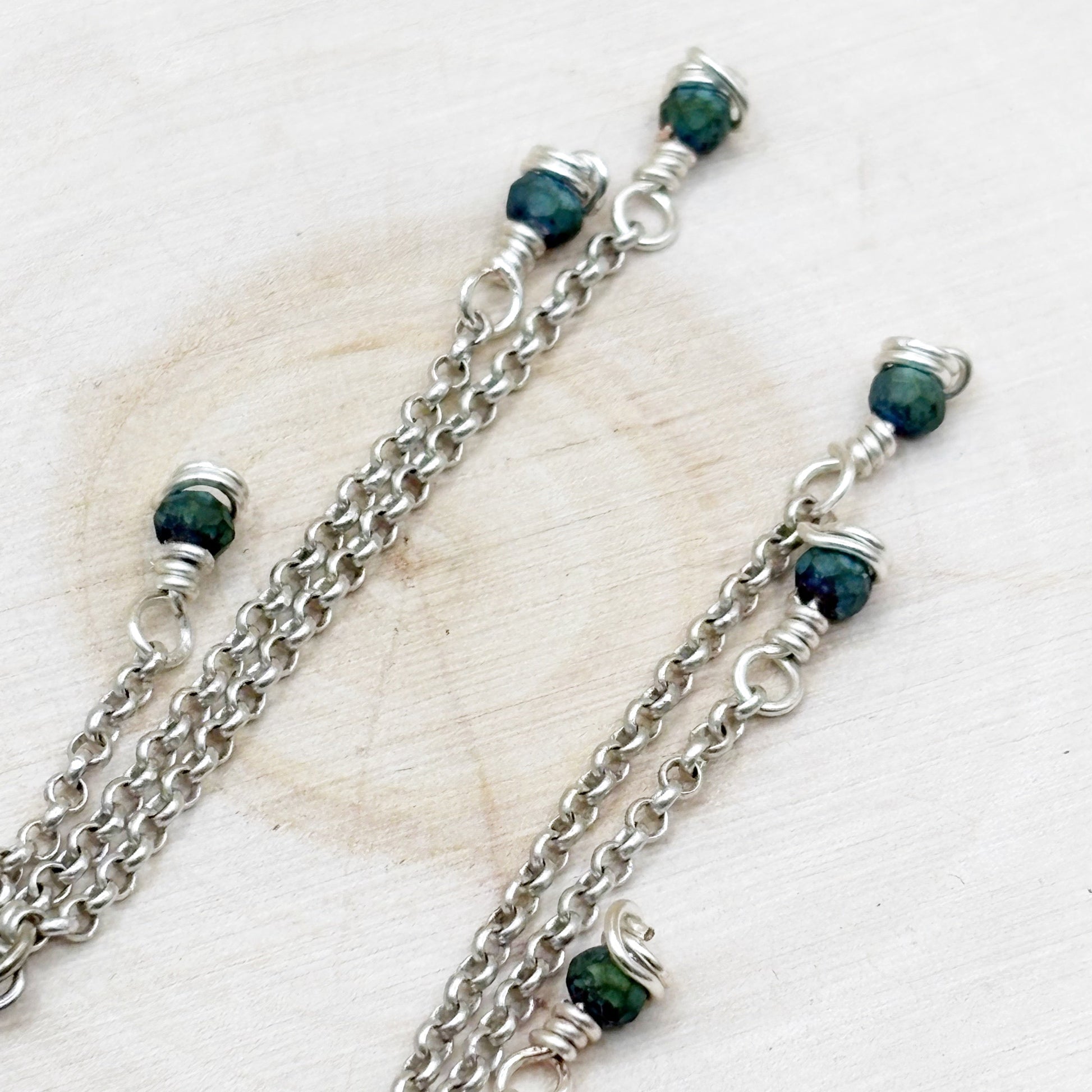 Silver chains with green beads on a light background