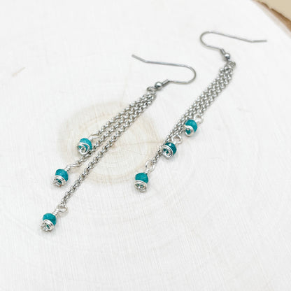 Silver chain earrings with turquoise beads on a white background