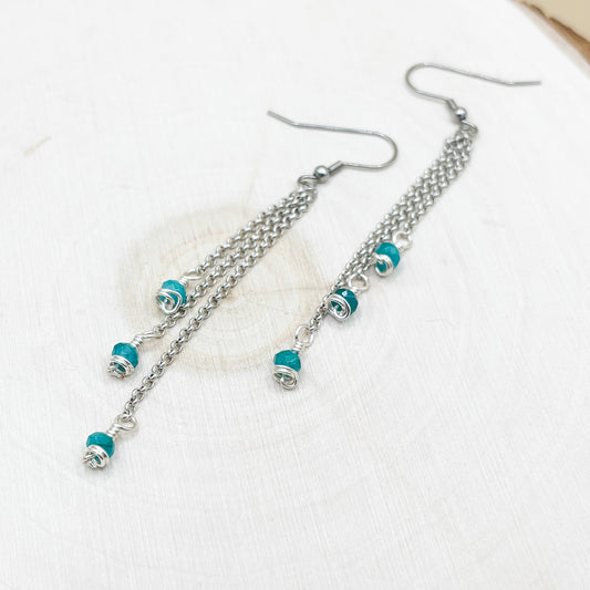 Silver chain earrings with turquoise beads on a white background