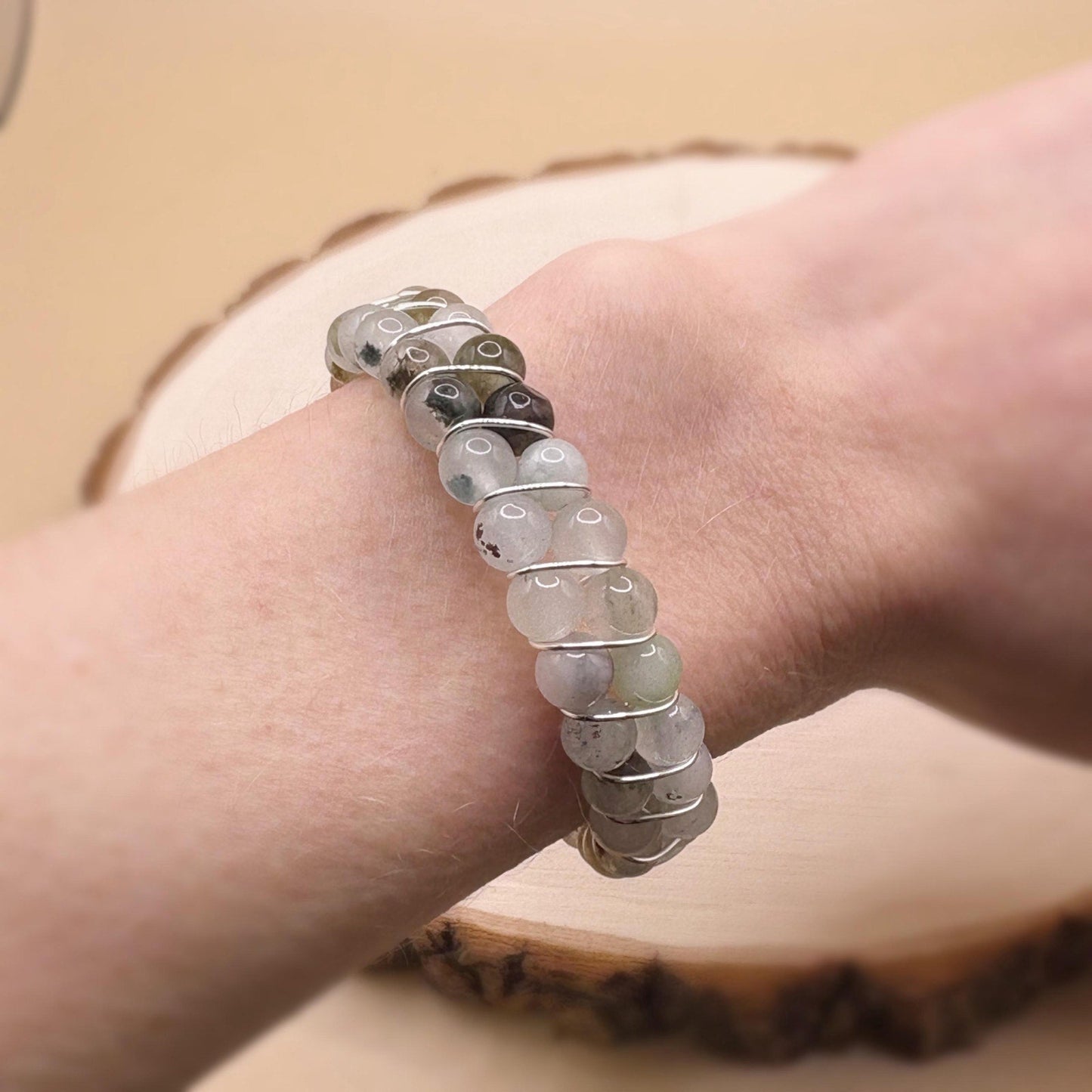 Close-up of a hand wearing a bracelet with blue transparent beads on a wooden surface