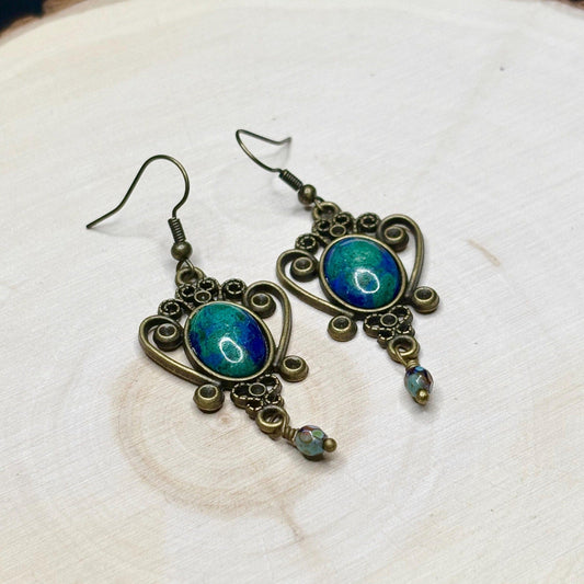 Ornate earrings with blue gemstones on a light background