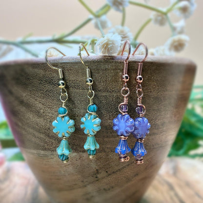 Blue and purple earrings hanging on a wooden bowl 