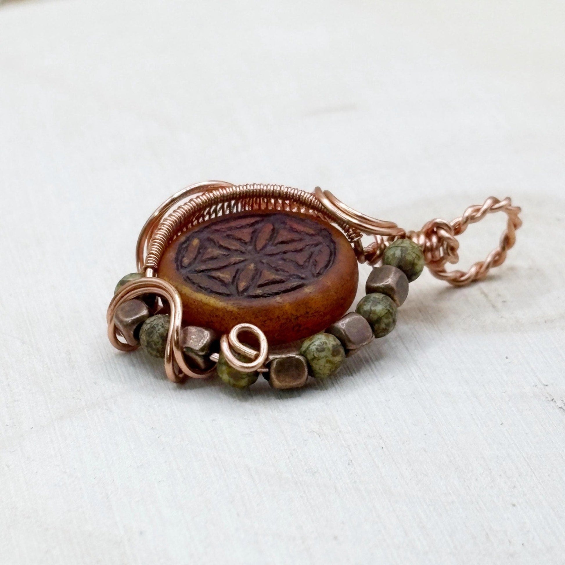 Copper and glass pendant with beads on a white background