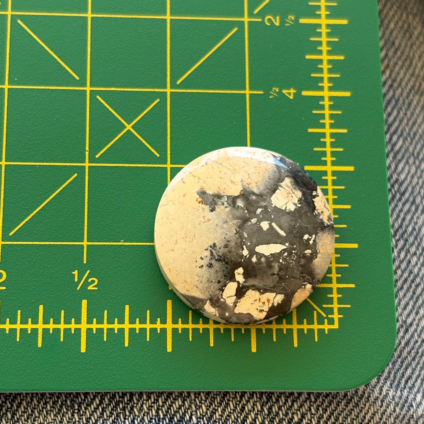 Round stone with black and white speckles on a green cutting mat with yellow grid lines