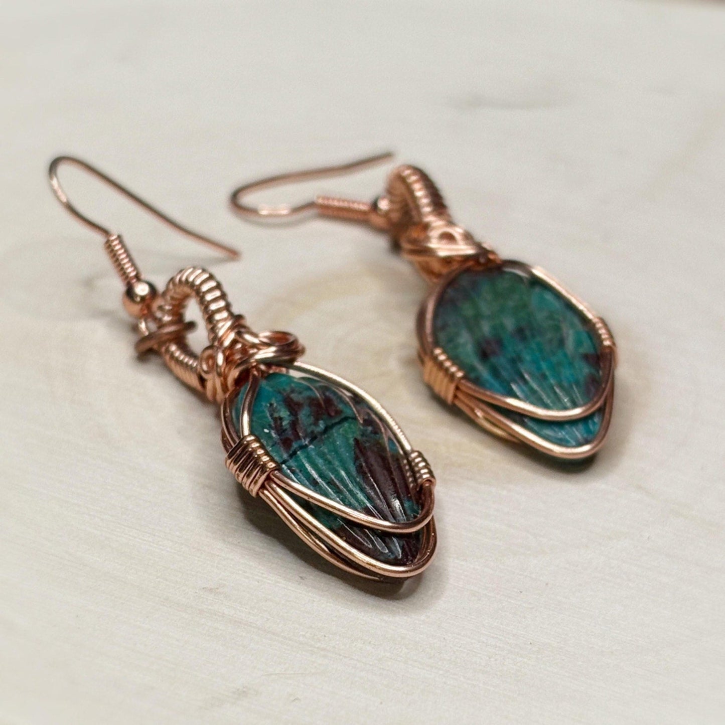 Chrysocolla stone earrings with copper wire wrapping on a light background