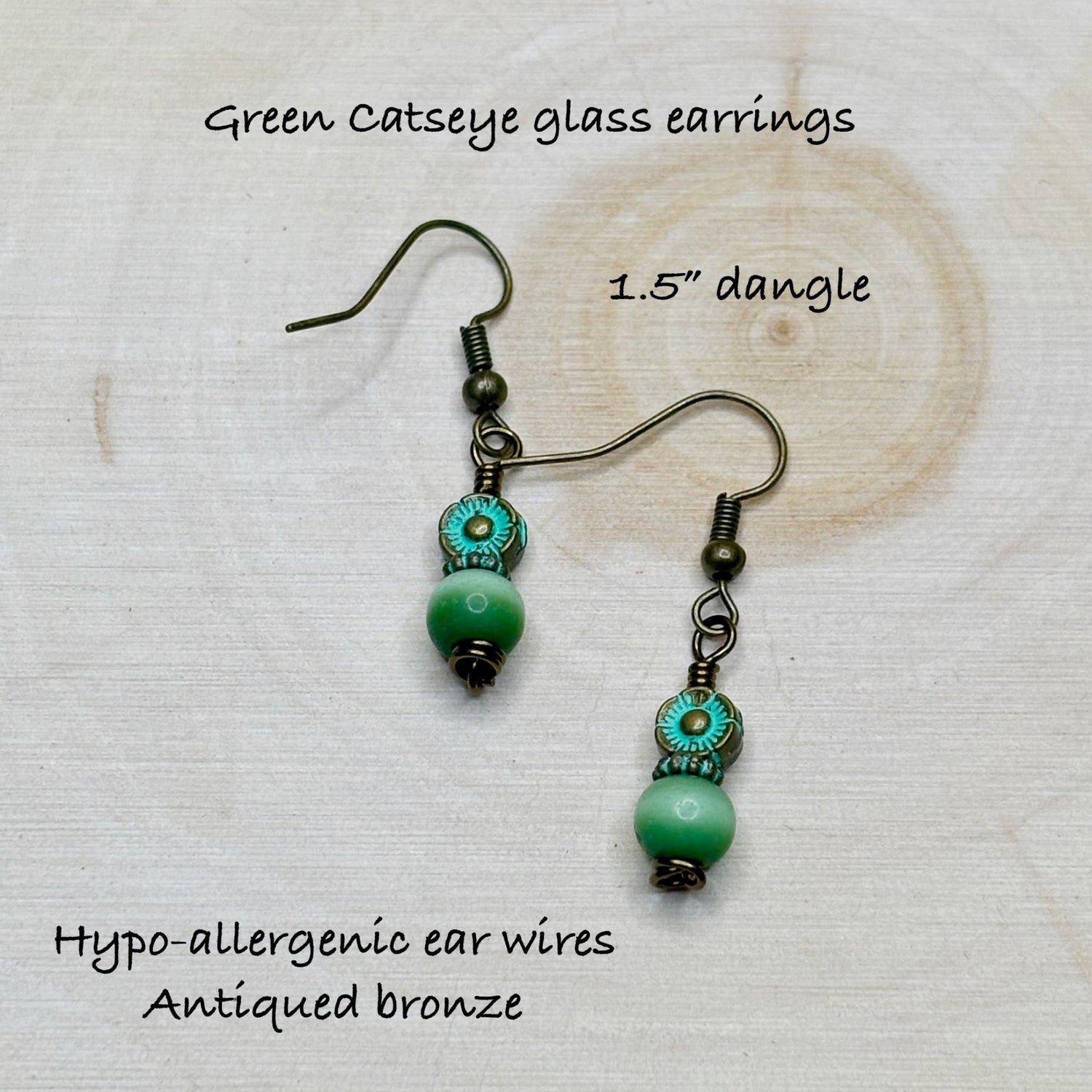 Green catseye glass earrings with hypo-allergenic ear wires on a textured white background