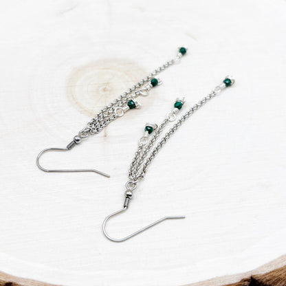 Silver earrings with green beads on a white background