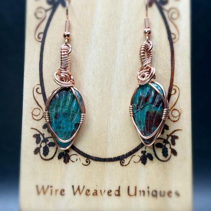 Pair of turquoise wire-wrapped earrings on a wooden display card with 'Wire Weaved Uniques' branding.
