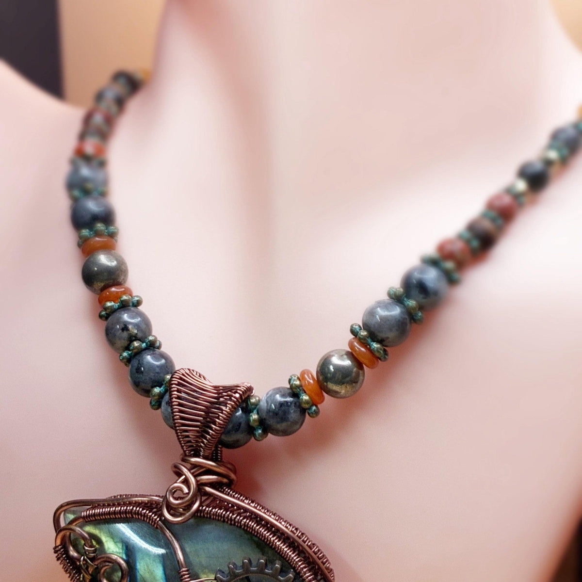 Necklace sitting on a dust showing off the beads on the necklace, gold, red, bronze and copper tones