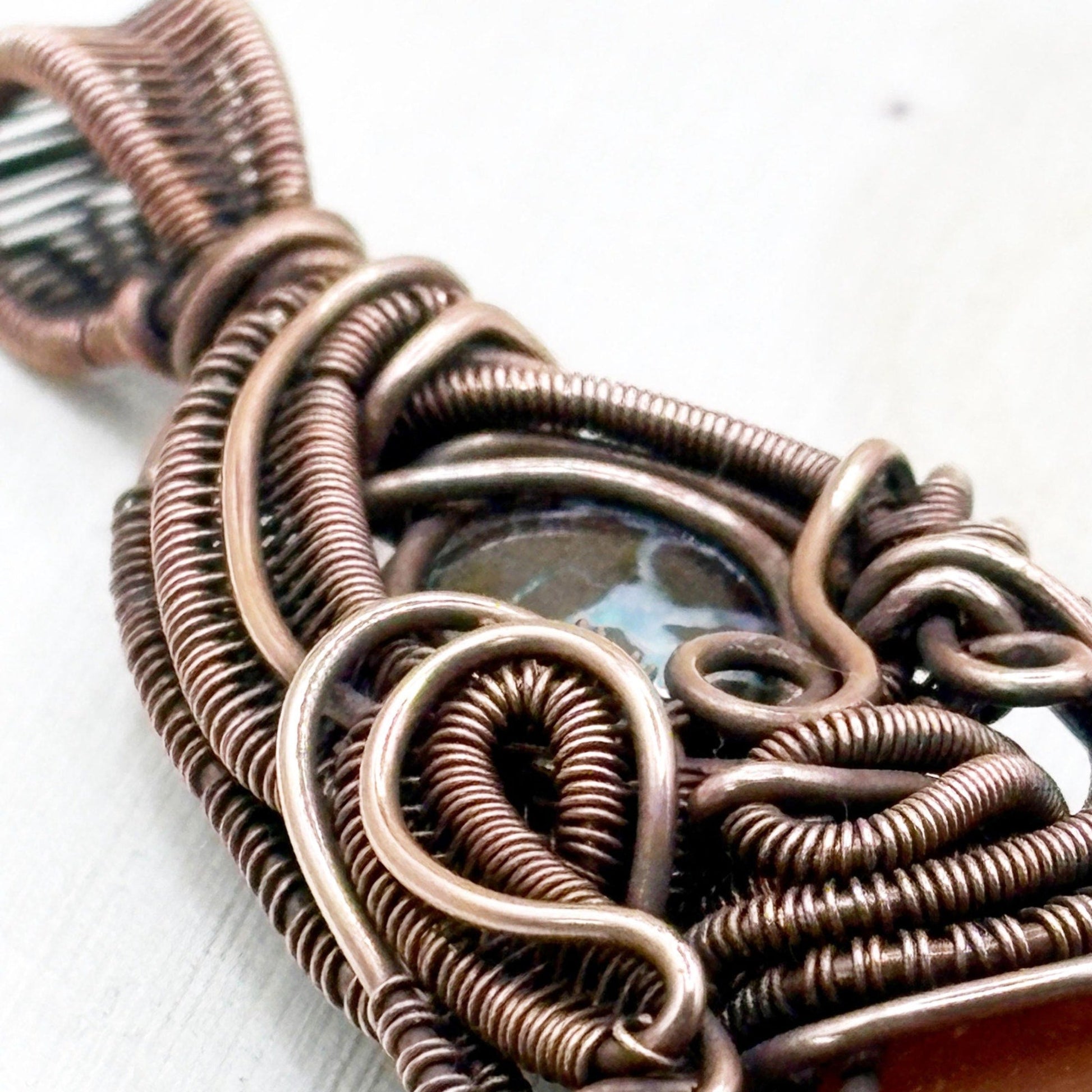 Close-up of a copper wire-wrapped pendant on a white background
