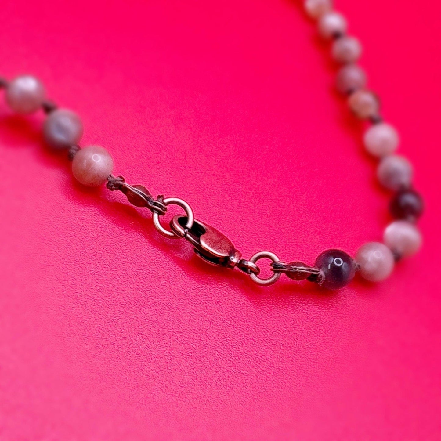 Necklace with beads and a clasp on a pink background