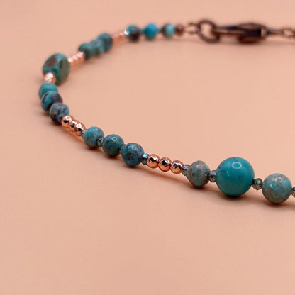 Beaded necklace with turquoise and copper beads on a beige background