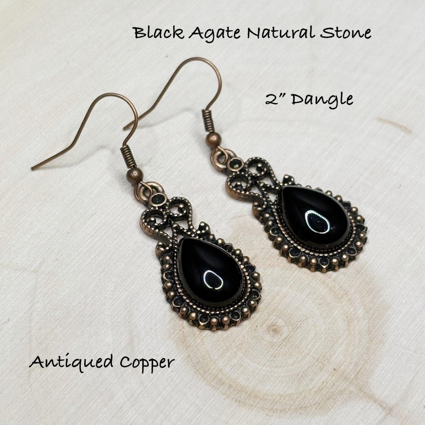 Black agate natural stone earrings with antiqued copper setting on a textured white surface.