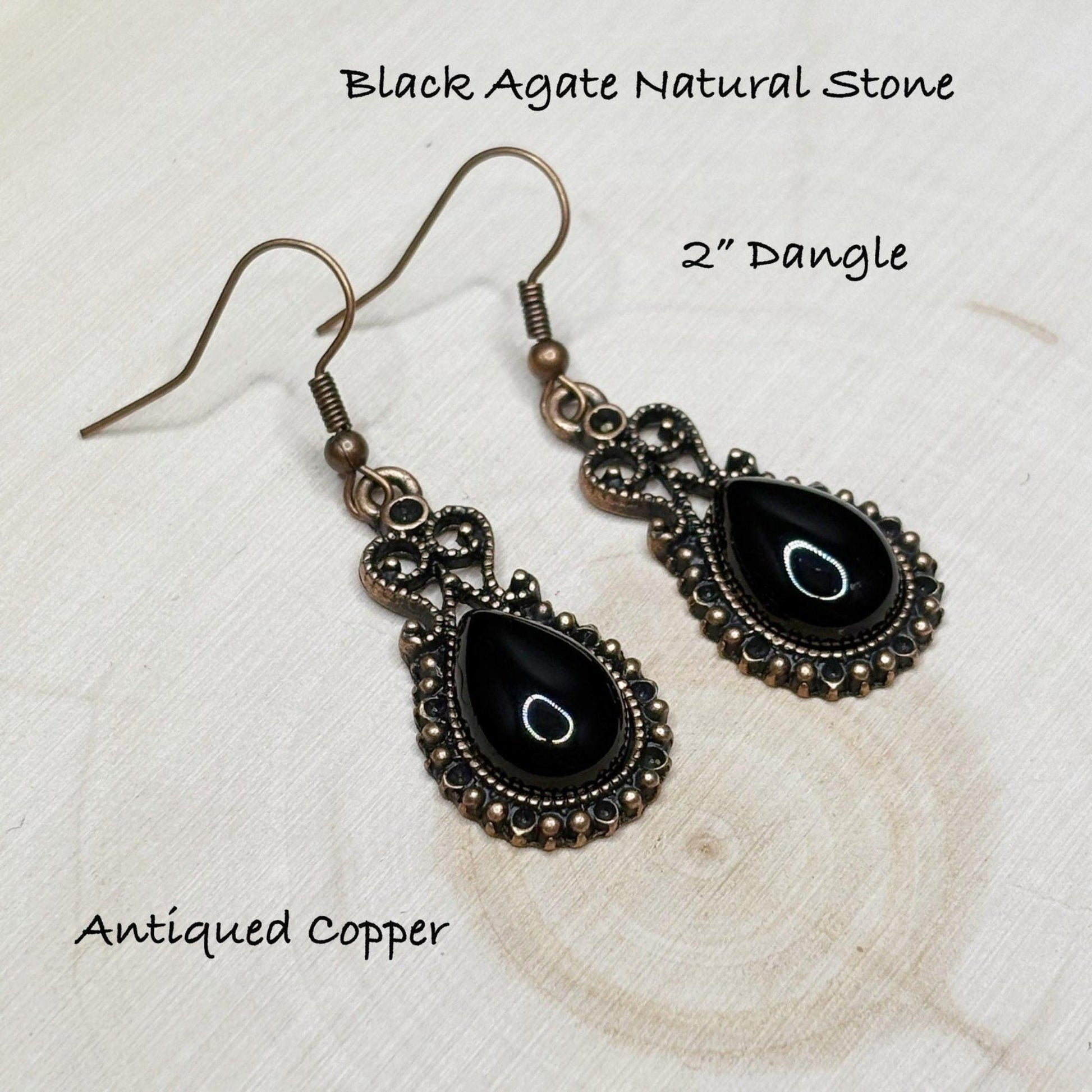 Black agate natural stone earrings with antiqued copper setting on a textured white surface.