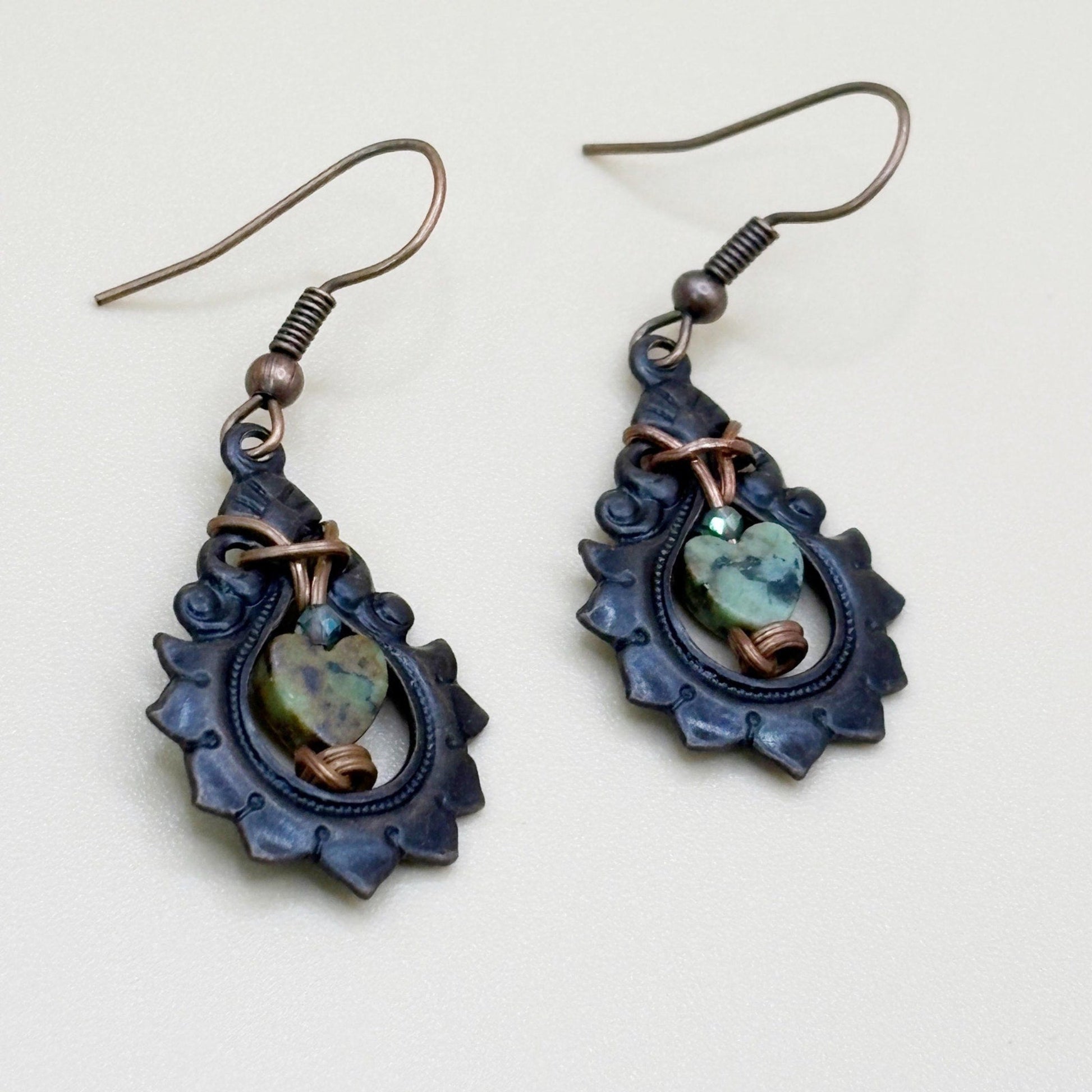 Pair of decorative earrings with blue and green stones on a light background