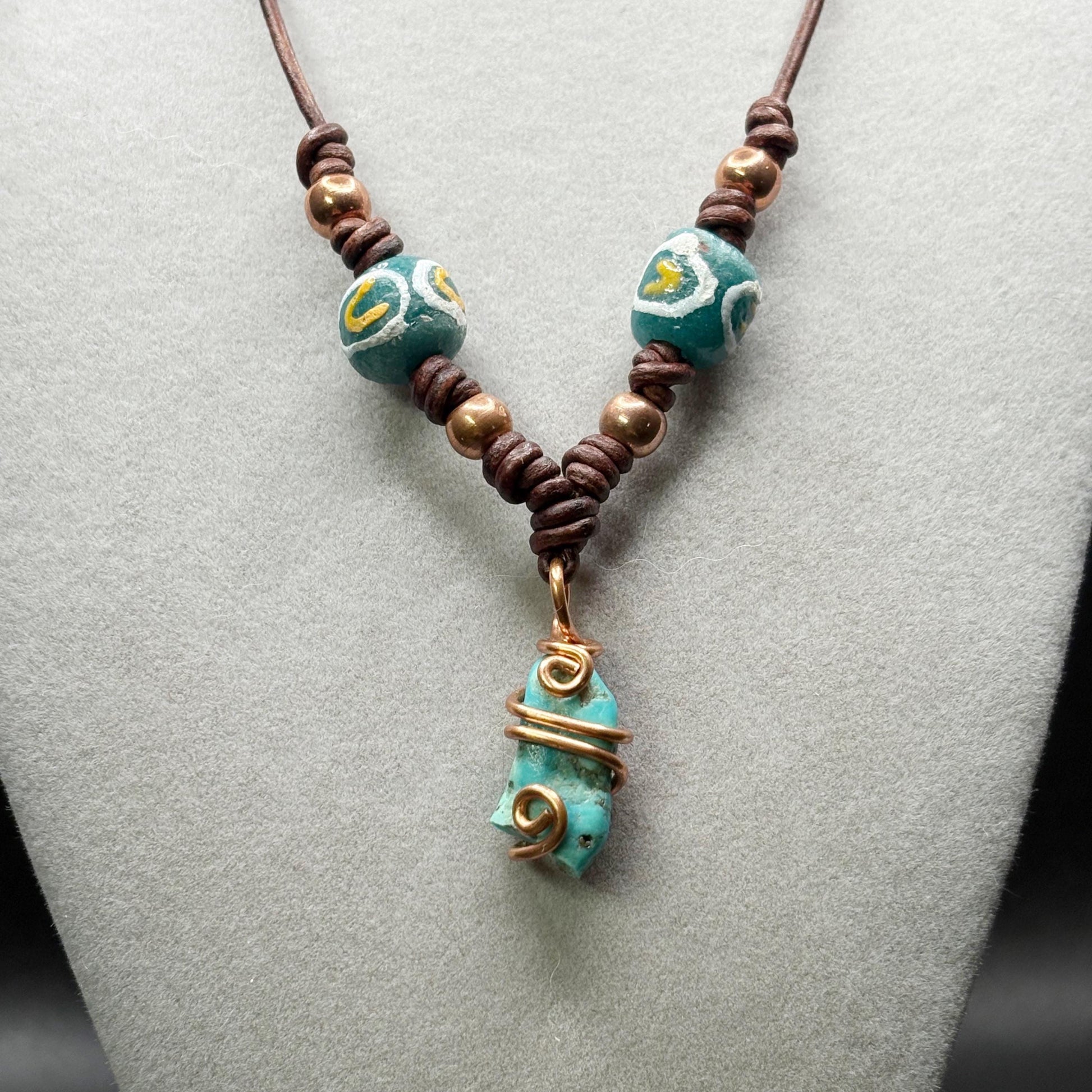 Necklace with turquoise beads and a decorative pendant on a gray surface