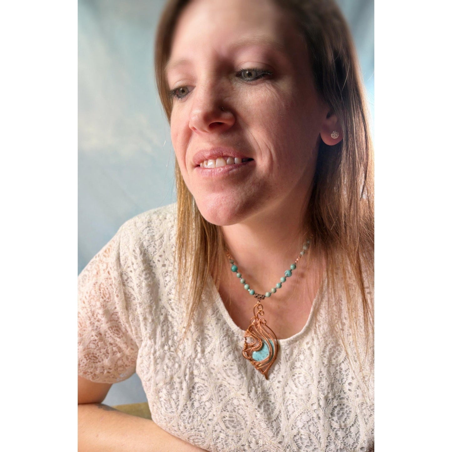 Woman wearing a necklace with a pendant against a neutral background