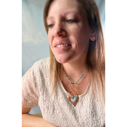 Woman wearing a necklace with a pendant against a neutral background