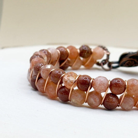Beaded bracelet with brown and orange sunstone stones on a white wood surface