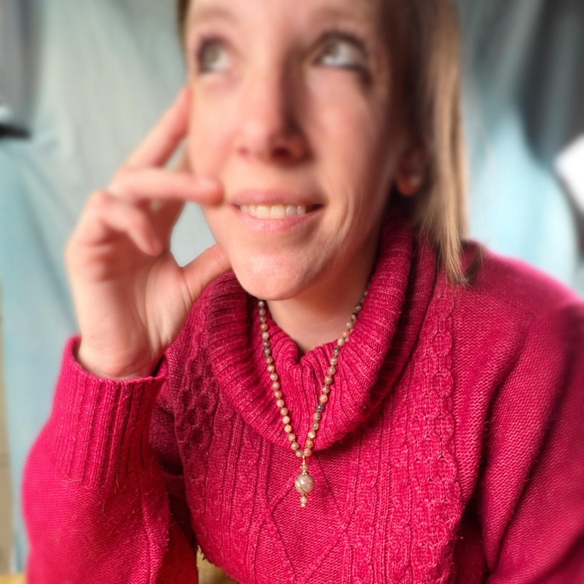 Person wearing a pink sweater with a blurred background