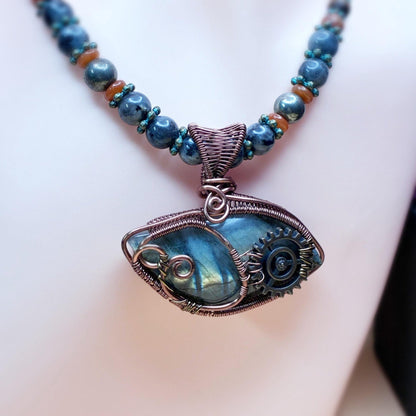 Necklace sitting on a bust featuring a beaded necklace and a copper wire wrap pendant focal