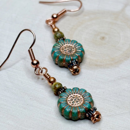 Pair of earrings with turquoise and copper floral designs on a light background
