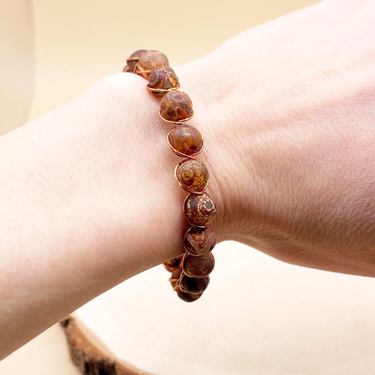 Brown tibetan agate beaded bracelet on a wrist with a neutral background
