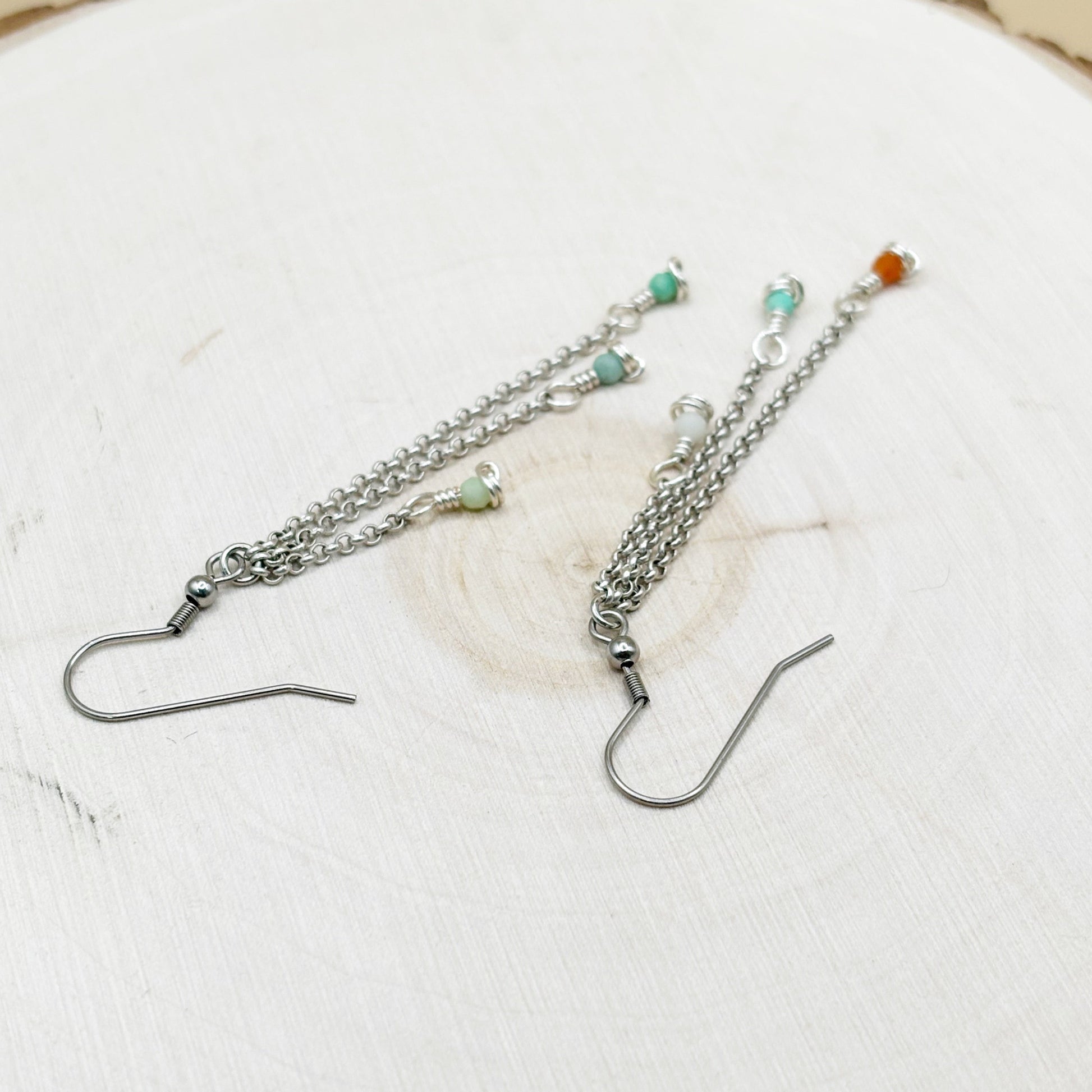 Two silver earrings with beads on a white surface