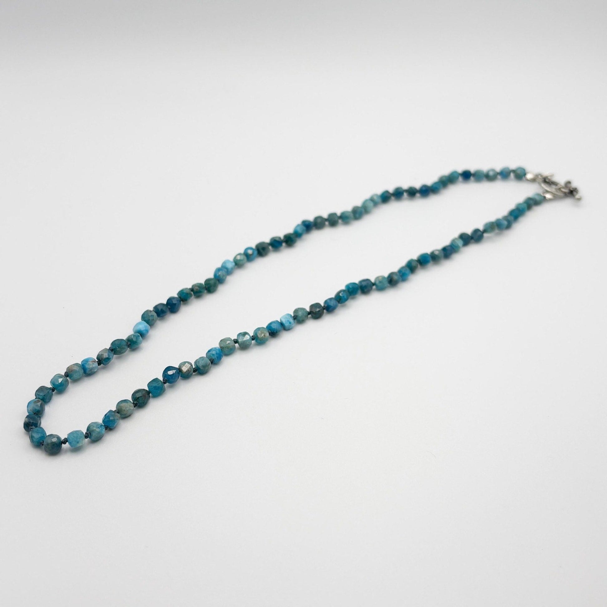 Blue beaded necklace on a light gray background