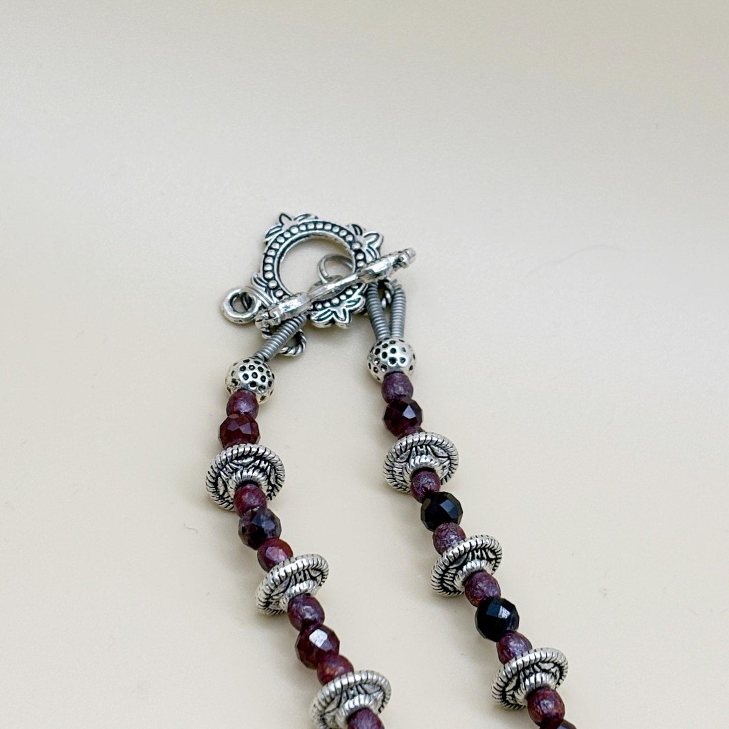 Necklace with purple beads and silver accents on a light background