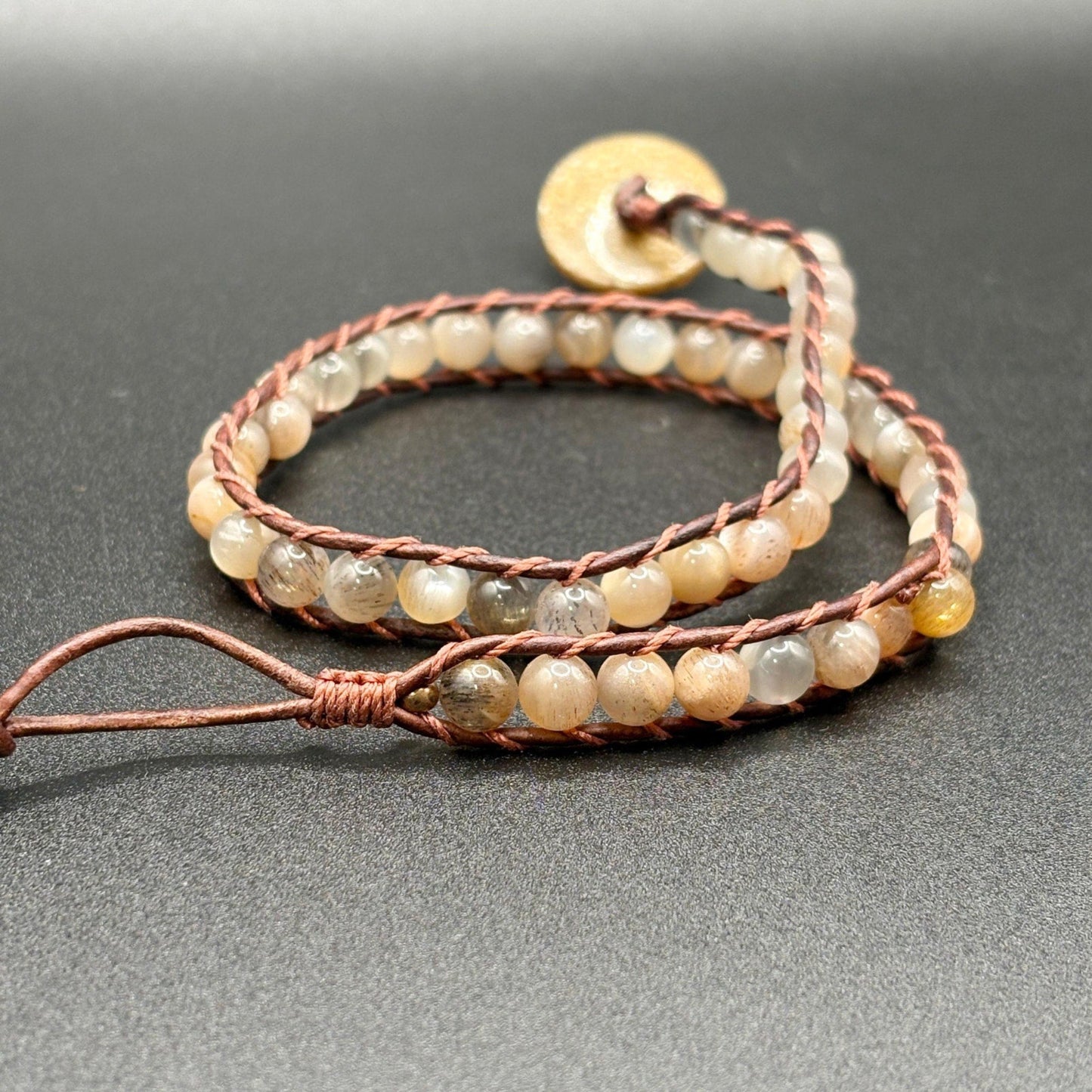 Beaded bracelet with brown cord on a gray background