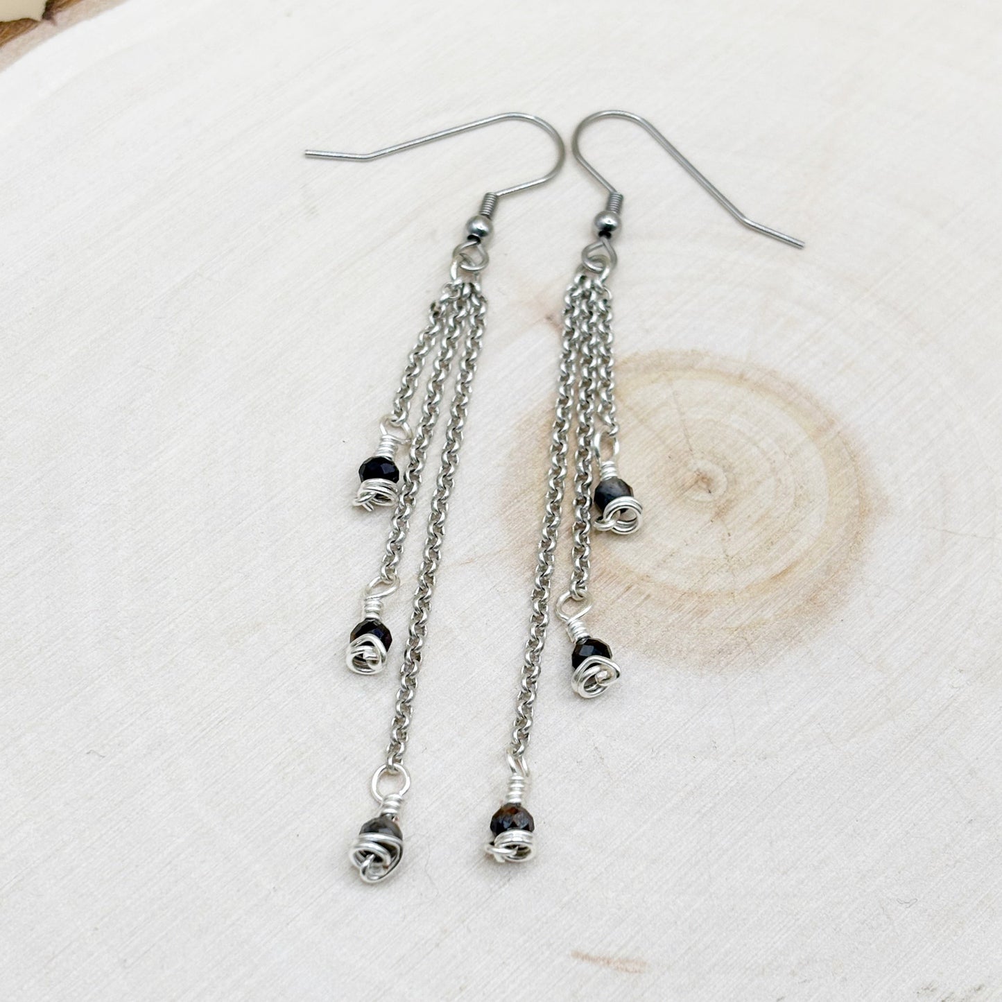 Silver chain earrings with blue beads on a light background