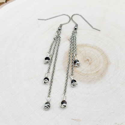 Silver chain earrings with blue beads on a light background
