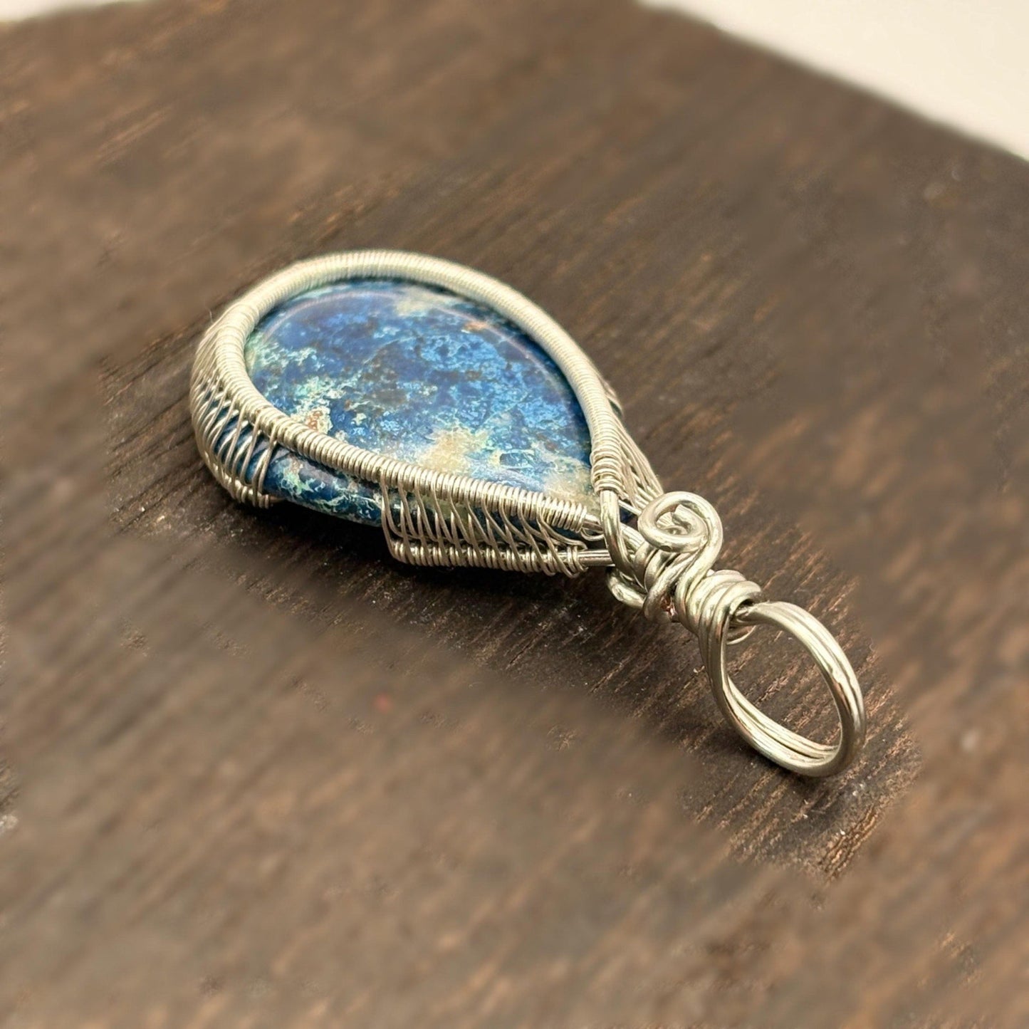 Silver pendant with a blue stone on a wooden surface