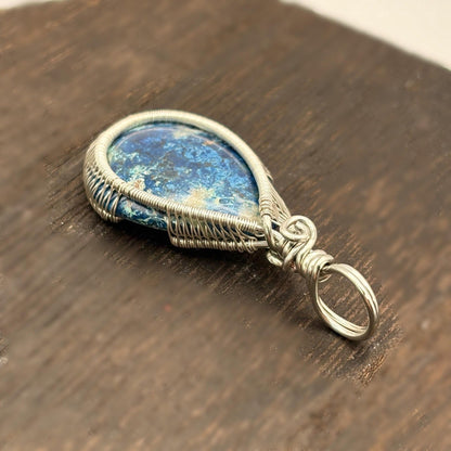 Silver pendant with a blue stone on a wooden surface