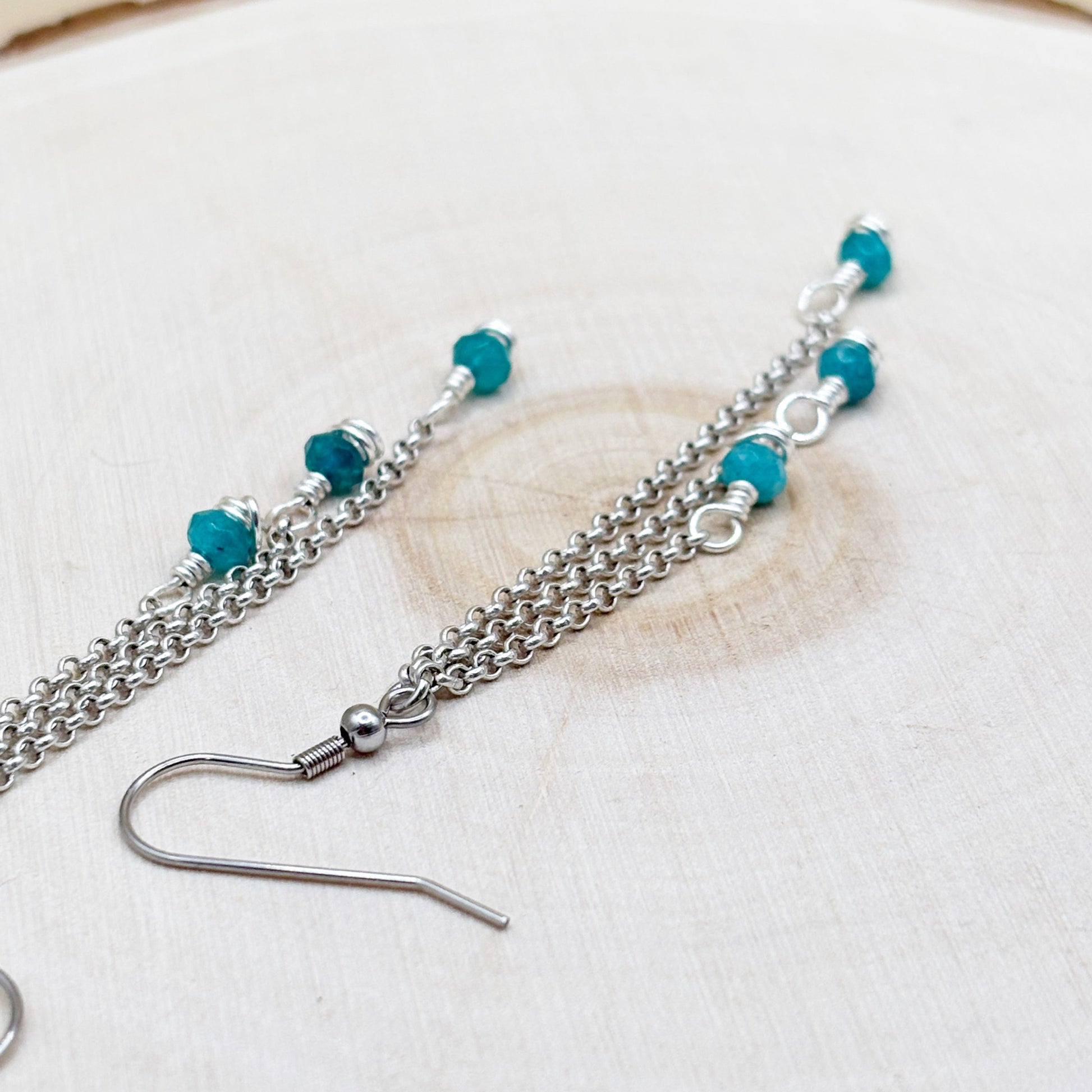 Silver chain earring with turquoise beads on a light background